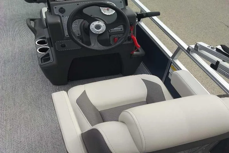 Slide: The Image of Interior of 2026 Sun Tracker Bass Buggy 16 XL Select pontoon boat, featuring steering console and seating. - 2
