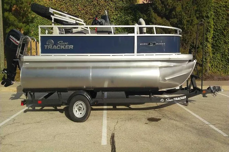 Slide: The Image of 2026 Sun Tracker Bass Buggy 16 XL Select pontoon boat on trailer in parking lot. - 14