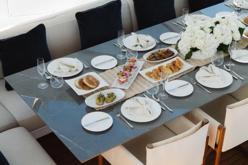 Slide: The Image of Elegant dining setup on Azimut yacht, featuring gourmet appetizers and floral centerpiece, 2023. - 64