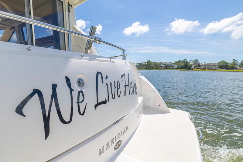 Slide: The Image of 2006 Meridian 341 Sedan yacht with "We Live Here" text, cruising on a sunny day. - 31