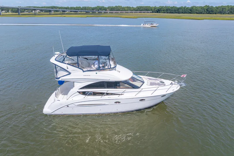 Slide: The Image of 2006 Meridian 341 Sedan yacht cruising on a calm river with scenic background. - 5