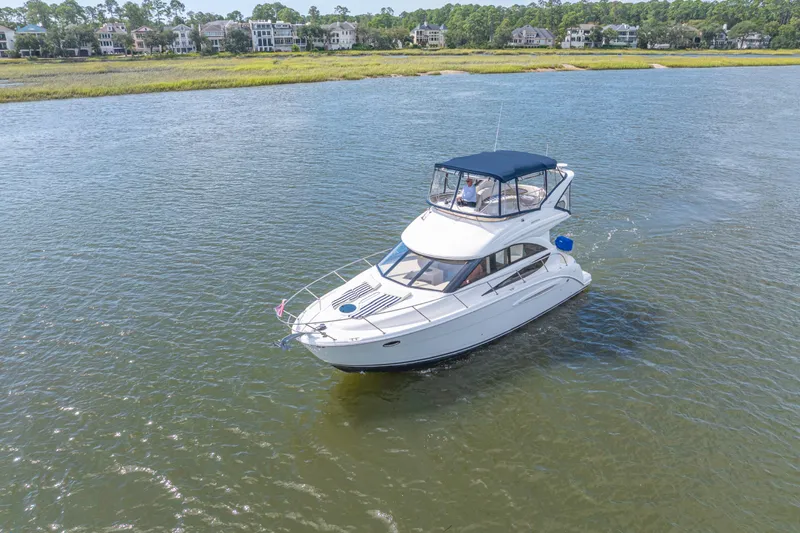 Slide: The Image of 2006 Meridian 341 Sedan cruising on a serene waterway near luxury homes. - 8