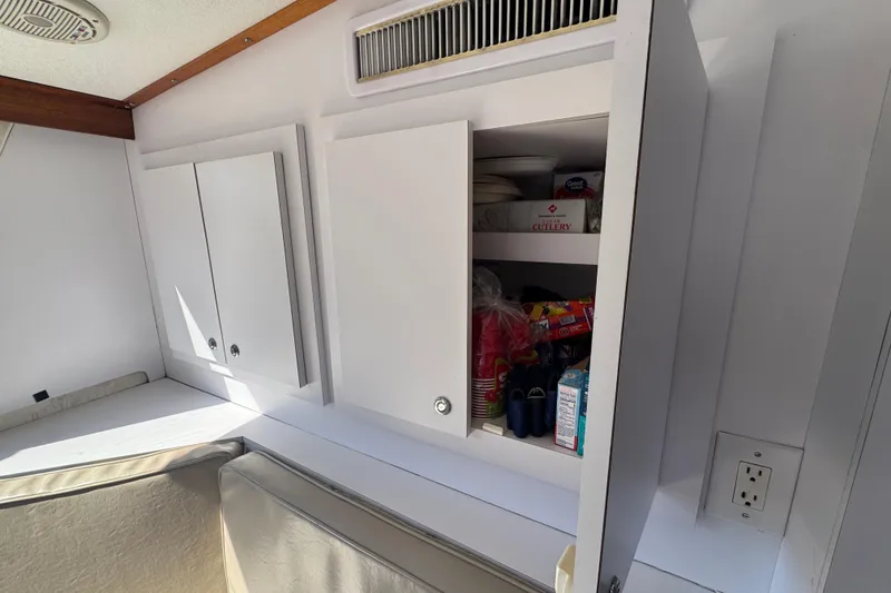 Slide: The Image of Interior of 1965 Hatteras 41 Convertible with open white cabinets and stored items. - 23