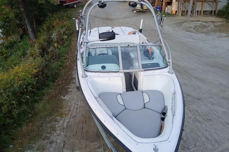 Slide: The Image of 2004 Correct Craft Super Air Nautique boat with sleek design, parked on a dirt path. - 22