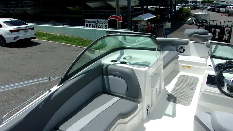 Slide: The Image of 2023 NauticStar 203 DC boat interior with gray seating and steering wheel, parked near rentals. - 18