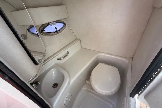 Slide: The Image of 2012 Sea Ray 300 Sundeck boat bathroom with sink, toilet, and porthole window. - 13