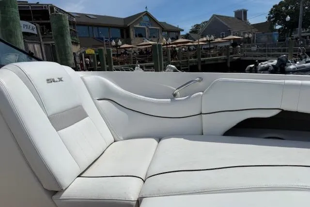 Slide: The Image of 2012 Sea Ray 300 Sundeck with white seating, docked near waterfront buildings. - 8
