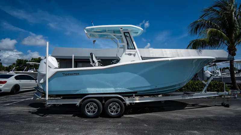 Slide: The Image of 2025 Tidewater 232 CC Adventure boat on a trailer, parked outdoors. - 0