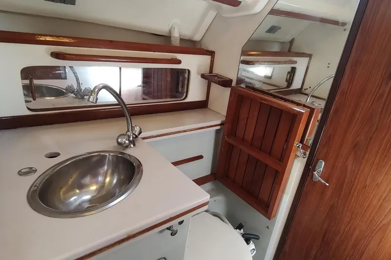 Slide: The Image of 1987 Hunter 37 Legend yacht bathroom with sink, mirror, and wooden cabinetry. - 32