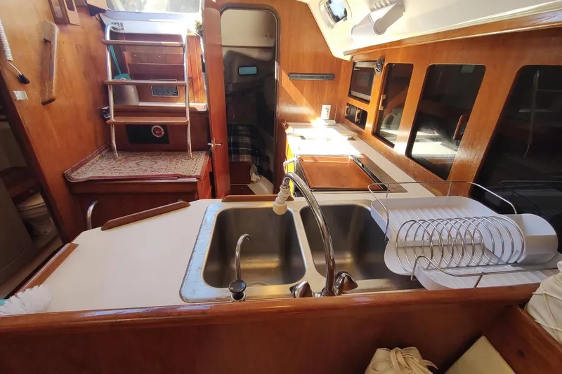 Slide: The Image of Interior of 1987 Hunter 37 Legend sailboat, featuring a compact kitchen with sink and wooden cabinetry. - 22