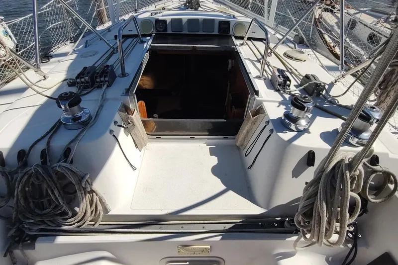 Slide: The Image of 1987 Hunter 37 Legend sailboat deck with ropes and winches, open hatch, and nautical equipment. - 12