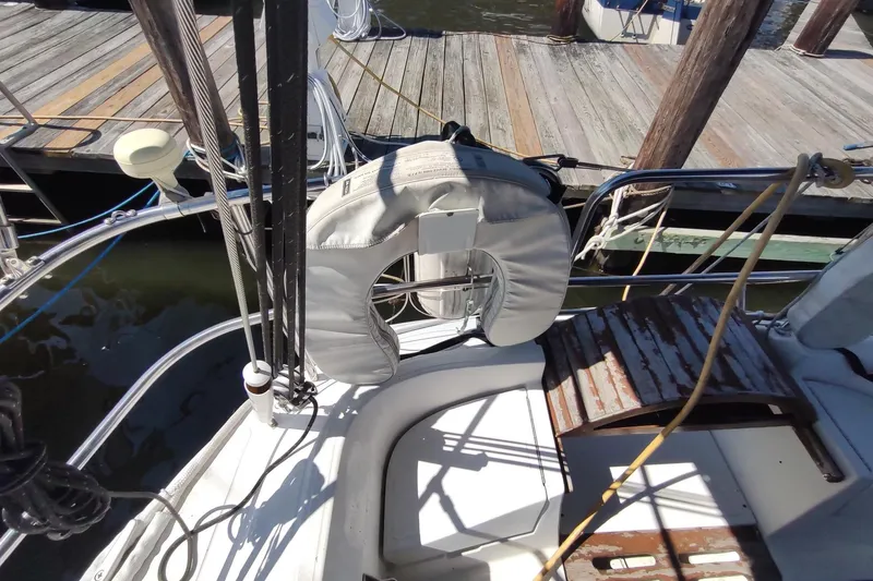 Slide: The Image of 1987 Hunter 37 Legend sailboat docked, featuring a life preserver and wooden deck details. - 8