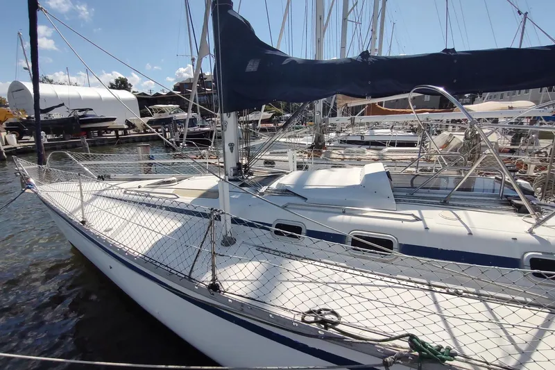 Slide: The Image of 1987 Hunter 37 Legend sailboat docked at marina, featuring sleek design and netted safety rails. - 2