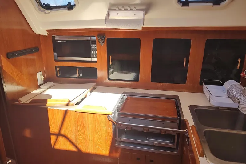 Slide: The Image of 1987 Hunter 37 Legend yacht kitchen with wooden cabinets, microwave, and stove. - 23