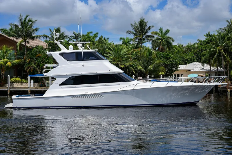 Slide: The Image of 2001 Viking 65 Enclosed Bridge yacht docked by tropical waterfront homes. - 2