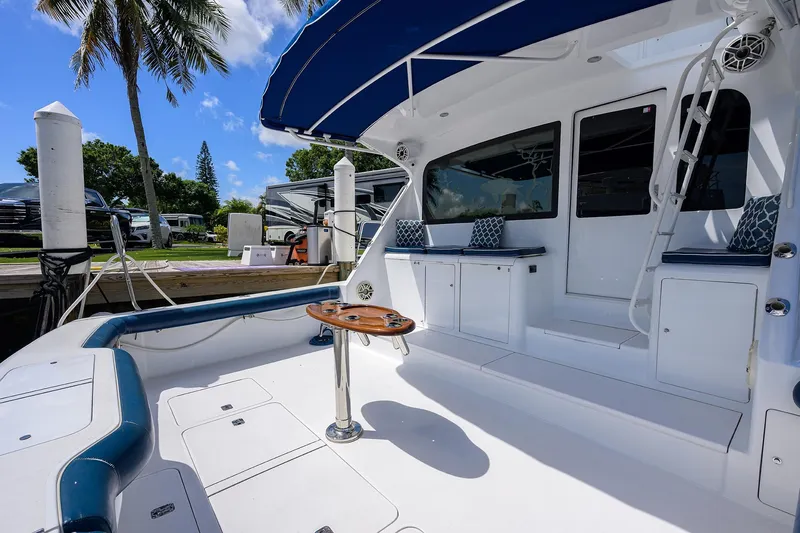 Slide: The Image of 2001 Viking 65 Enclosed Bridge yacht deck with seating, table, and blue canopy. - 21