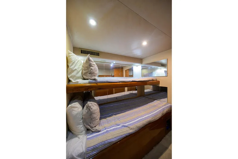 Slide: The Image of Bunk beds in 2001 Viking 65 Enclosed Bridge yacht cabin, featuring cozy bedding and ambient lighting. - 27