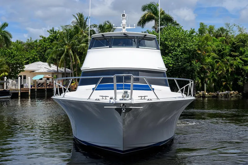 Slide: The Image of 2001 Viking 65 Enclosed Bridge yacht on a serene waterway, surrounded by lush greenery. - 5