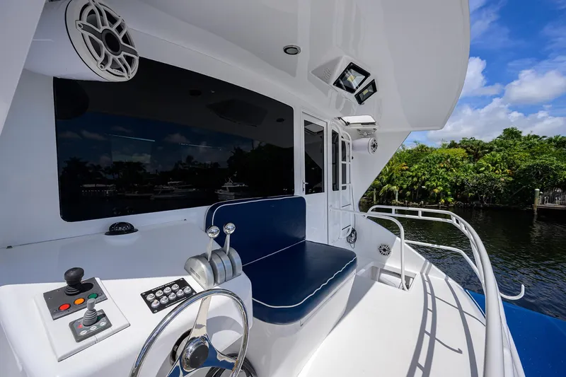 Slide: The Image of 2001 Viking 65 Enclosed Bridge yacht helm with controls, blue seating, and scenic water view. - 51