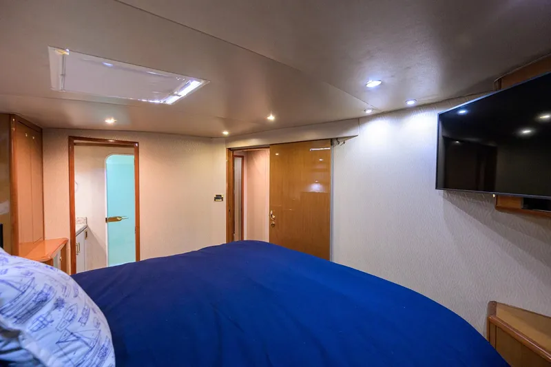 Slide: The Image of Interior of 2001 Viking 65 Enclosed Bridge yacht bedroom with TV and blue bedding. - 85