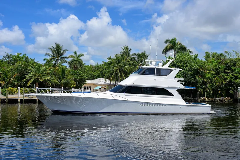 Slide: The Image of 2001 Viking 65 Enclosed Bridge yacht on calm water, surrounded by lush greenery. - 9