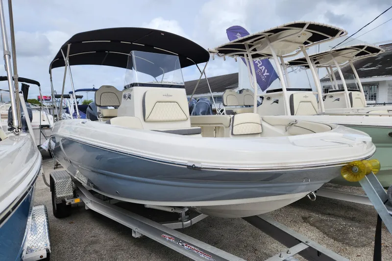 The Image of 2023 Stingray 206cc boat with canopy on trailer, displayed at a dealership. - 0