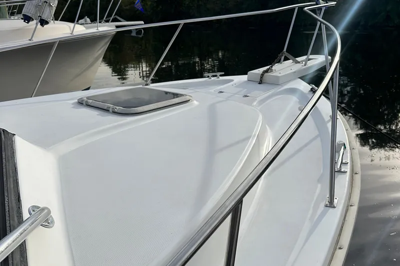Slide: The Image of 1998 Rampage 28 Express boat deck with railing and hatch, docked on calm water. - 5