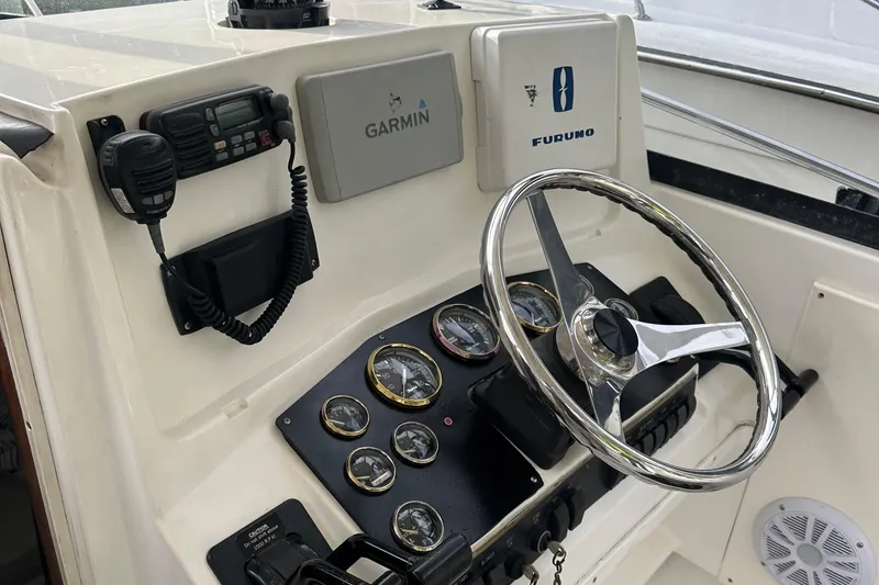 Slide: The Image of 1998 Rampage 28 Express helm with Garmin and Furuno navigation systems, steering wheel, and gauges. - 7