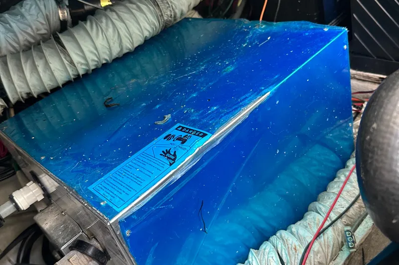 Slide: The Image of Blue engine cover in a 1998 Rampage 28 Express boat, surrounded by hoses and wires. - 8