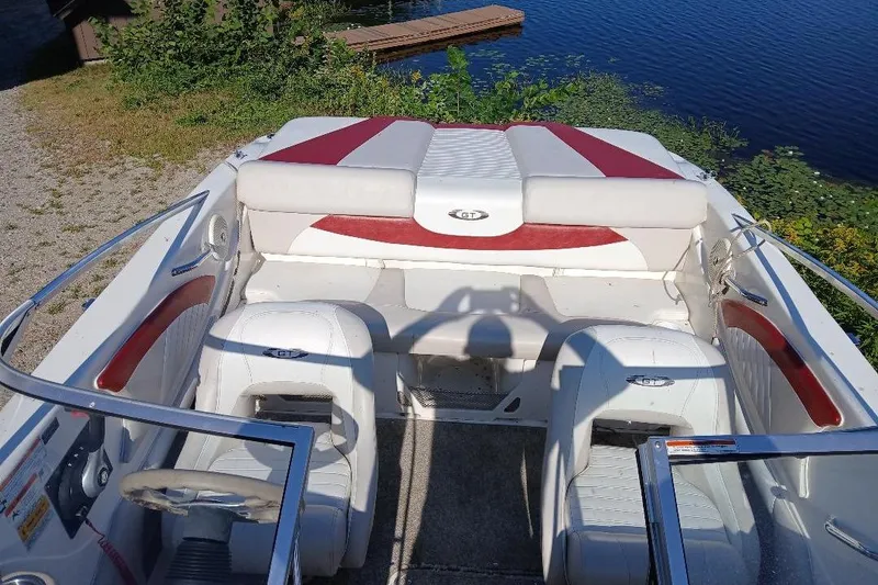 Slide: The Image of 2007 Glastron GT 185 boat interior with white and red seating near a lake. - 3