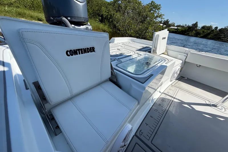 Slide: The Image of 2024 Contender 26 Bay boat interior with seating and storage, near water. - 11