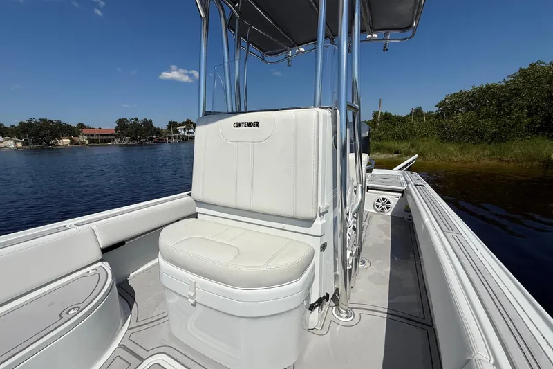 Slide: The Image of 2024 Contender 26 Bay boat interior with white seating and console, on calm water. - 34