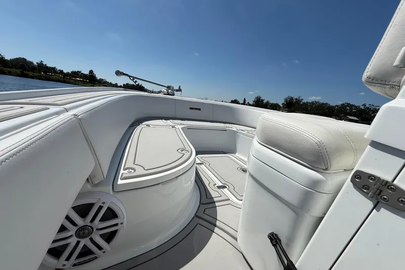 Slide: The Image of 2024 Contender 26 Bay boat interior with white seating and speaker, under clear blue sky. - 38