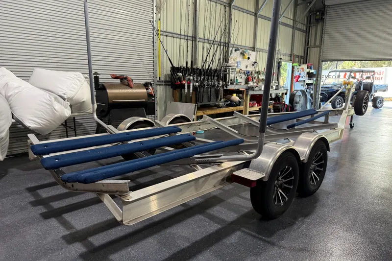 Slide: The Image of 2024 Contender 26 Bay boat trailer in a workshop with fishing gear and equipment. - 49