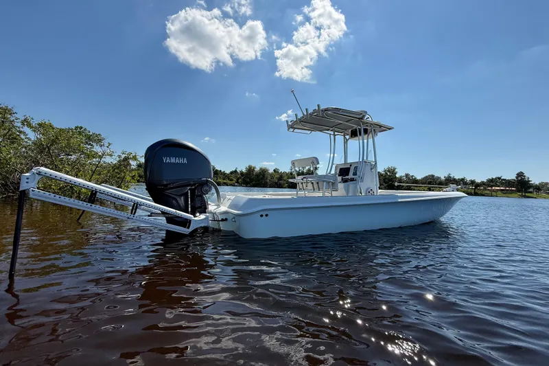 Slide: The Image of 2024 Contender 26 Bay boat on calm water with Yamaha engine, under clear blue sky. - 9