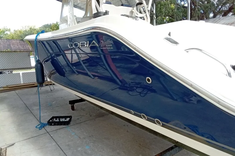 Slide: The Image of 2014 Cobia 296 Center Console boat with blue hull, docked and secured with a rope. - 10