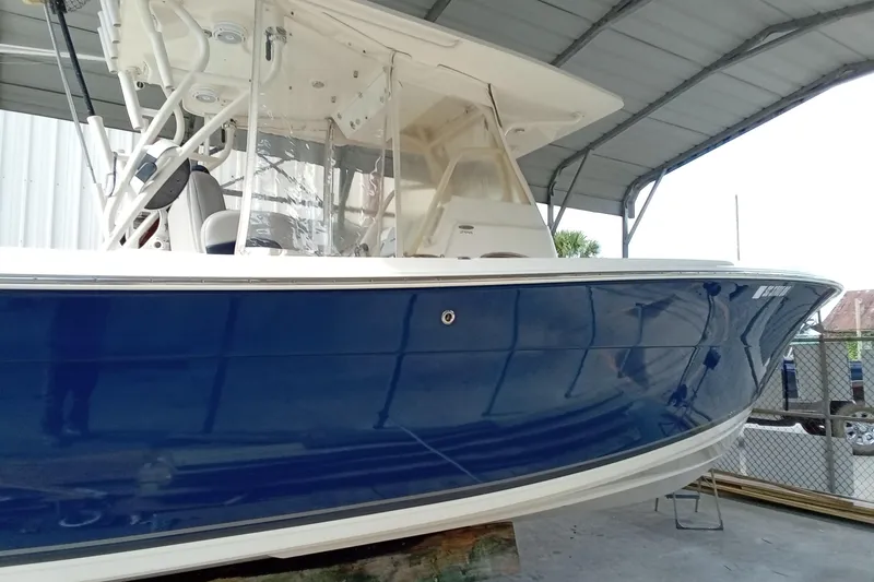 Slide: The Image of 2014 Cobia 296 Center Console boat with blue hull under a canopy. - 21