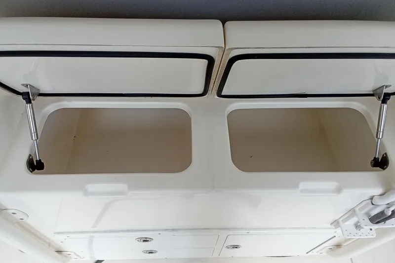 Slide: The Image of 2014 Cobia 296 Center Console storage compartments with open lids and hydraulic supports. - 23