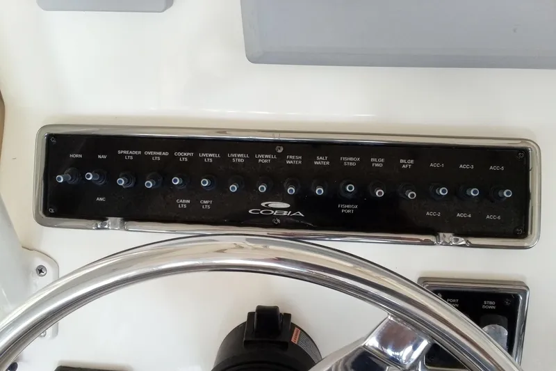 Slide: The Image of Control panel of a 2014 Cobia 296 Center Console boat with labeled switches. - 27