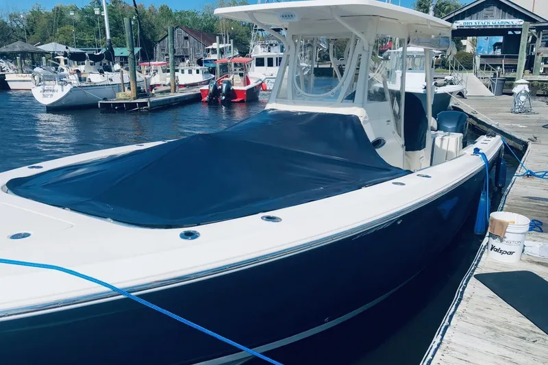 Slide: The Image of 2014 Cobia 296 Center Console boat docked at marina with cover. - 4