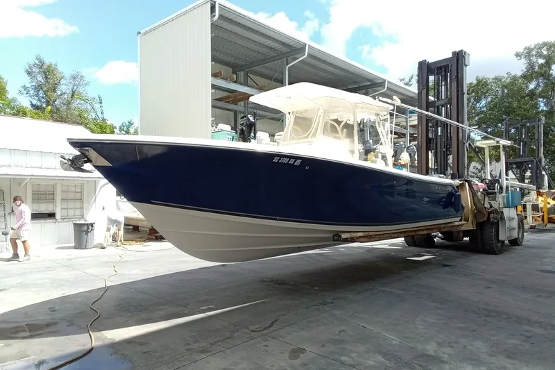Slide: The Image of 2014 Cobia 296 Center Console boat on forklift at marina, blue hull, sunny day. - 52