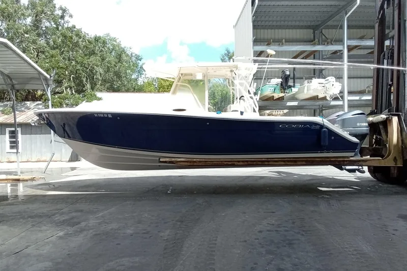 Slide: The Image of 2014 Cobia 296 Center Console boat on forklift, blue hull, outdoor storage area. - 53
