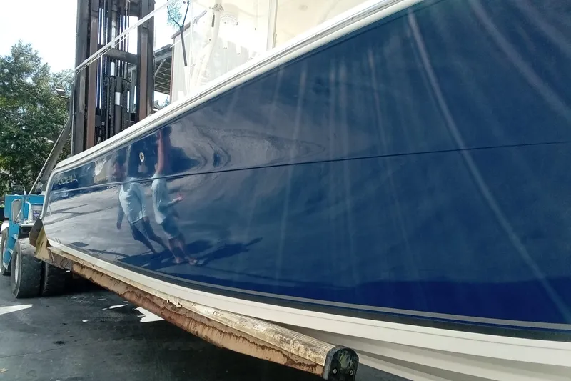 Slide: The Image of 2014 Cobia 296 Center Console boat with sleek blue hull on a forklift. - 55