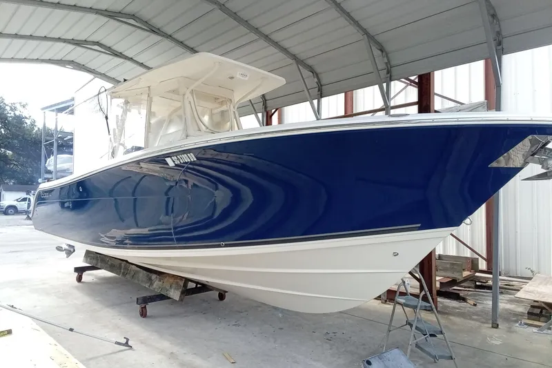 Slide: The Image of 2014 Cobia 296 Center Console boat with blue hull under a metal canopy. - 8