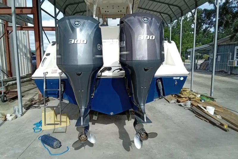 Slide: The Image of 2014 Cobia 296 Center Console with twin Yamaha 300 engines in a covered dock. - 9