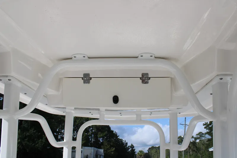 Slide: The Image of 2023 Robalo 226 Cayman boat T-top storage compartment, white finish, outdoor setting. - 19