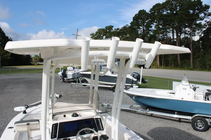 Slide: The Image of 2023 Robalo 226 Cayman boat with T-top and rod holders, parked outdoors. - 20