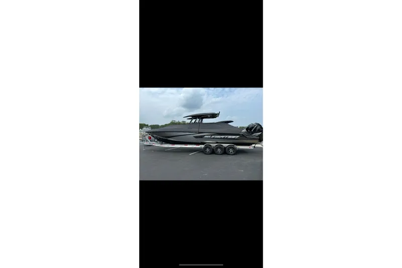 Slide: The Image of 2023 Sunsation 32 CCX boat on trailer, parked outdoors under cloudy sky. - 2