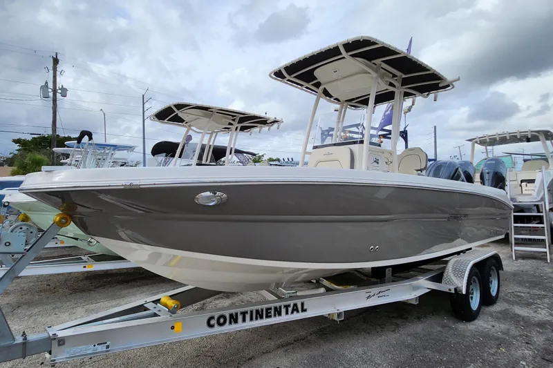 Slide: The Image of 2023 Stingray 236 CC boat on trailer, displayed outdoors under cloudy sky. - 0