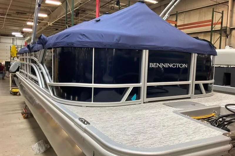Slide: The Image of 2026 Bennington 22 SSRSE pontoon boat with blue cover in a warehouse setting. - 10